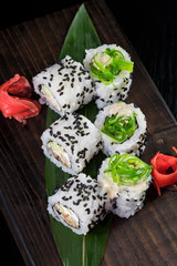 Japanese traditional rolls with seafood and fish, vegetables, on a black background.