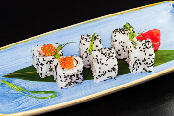 Japanese traditional rolls with seafood and fish, vegetables, on a black background.