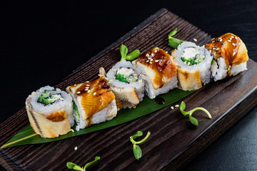 Japanese traditional rolls with seafood and fish, vegetables, on a black background.
