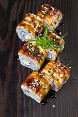 Japanese traditional rolls with seafood and fish, vegetables, on a black background.