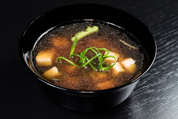 Asian noodles with vegetables and meat on a black background.