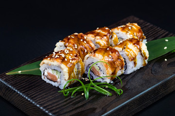 Japanese traditional rolls with seafood and fish, vegetables, on a black background.