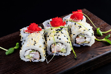 Japanese traditional rolls with seafood and fish, vegetables, on a black background.