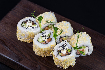 Japanese traditional rolls with seafood and fish, vegetables, on a black background.