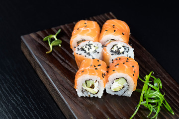 Japanese traditional rolls with seafood and fish, vegetables, on a black background.