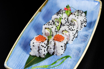 Japanese traditional rolls with seafood and fish, vegetables, on a black background.