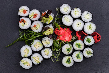 Japanese traditional rolls with seafood and fish, vegetables, on a black background.