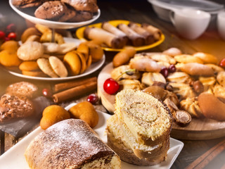 Oatmeal cookies and sand chocolate cake with cherry berry and crispy wafer rolls with cream on cutting board on wooden table in rustic style. Cherry in powdered sugar.