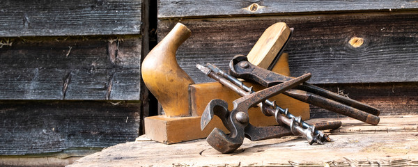 Antique hand tools plane pincers and drills. Old brown boards. Copy space, panoramic photo.