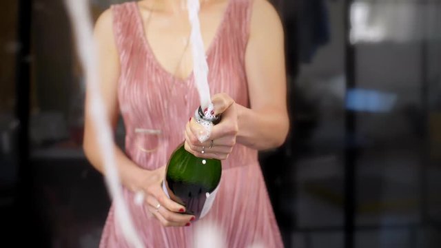 Anonymous woman shaking bottle of champagne in slow motion