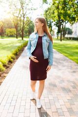 Happy pregnant girl walks in the park