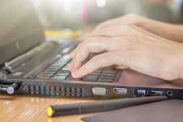 Closeup image of hand using and touching on laptop on wooden table.