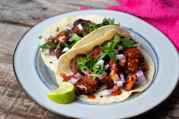 Mexican food: Delicious red chorizo tacos on wooden background