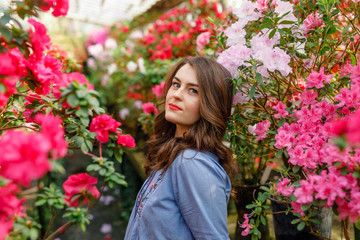 Naklejka premium portrait of a young beautiful woman in a blue dress in a beautiful botanic garden with flowers