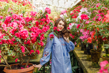 portrait of a young beautiful woman in a blue dress in a beautiful botanic garden with flowers