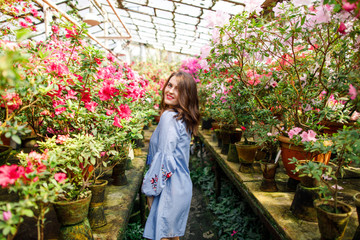 portrait of a young beautiful woman in a blue dress in a beautiful botanic garden with flowers