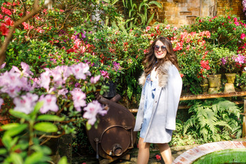 portrait of a young beautiful woman in a blue dress in a beautiful botanic garden with flowers