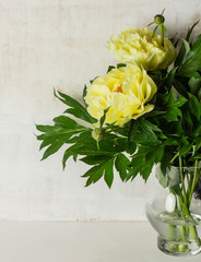 A beautiful bouquet of yellow peonies in a glass vase.