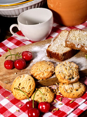 Oatmeal cookies and cherry on kitchen cutting board gingham checkered cotton fabric on table in village style for picnic. Cooking at home. Classic ingredients of French cuisine.