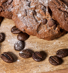 Oatmeal chocolate cookies with coffee grains, powdered sugar on kitchen cutting board with checkered fabric on wooden table in village style for picnic. Close-up dietary dishes. Top view.