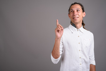 Young businessman with dreadlocks against gray background