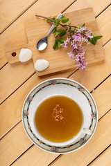 Delicious tea in a cup on a wooden table with the addition of lilac flowers. A healthy cold infusion prepared in the home kitchen.