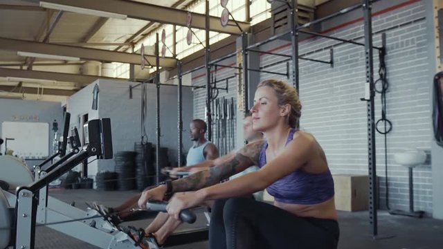 Fit healthy people on rowing machines in gym