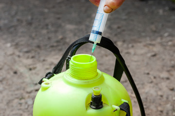 man fill syringe with pesticide for sprayer