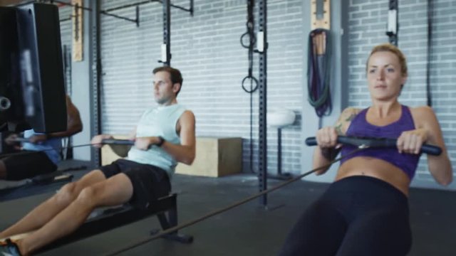 woman with tattoos exercising rowing in gym