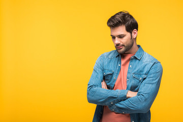 handsome pensive man with crossed arms Isolated On yellow