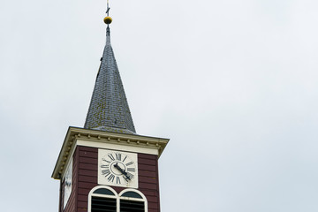 Isolated in white sky church clock tower in romal numerals. Old looking village small clock tower....