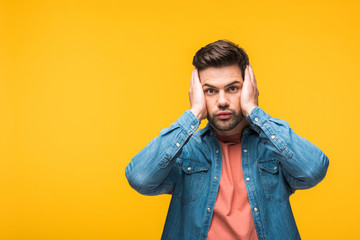 Obraz premium shocked handsome man with hands on head Isolated On yellow with copy space