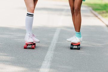 partial view of two girls skateboarding on penny boards on road