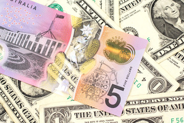 A close up image of an Australian five dollar bill with United States one dollar bills in macro