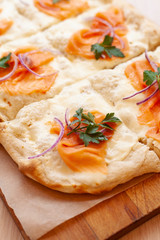Roman pizza with smoked salmon cut in pieces and served on a wooden board