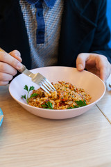 Man is having pearl barley with grilled bacon and sweet'n'sour sause for lunch in a cafe