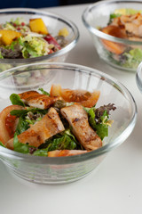 Multiple of salads with fresh veggies in glass bowls on a white table