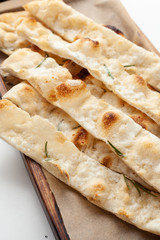 Simple italian focaccia with cheese and herbs served as an appetizer on a board