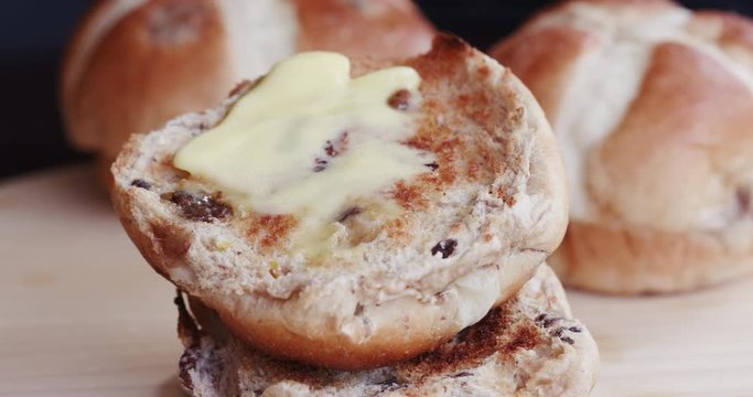 Butter being spread onto a hot cross bun