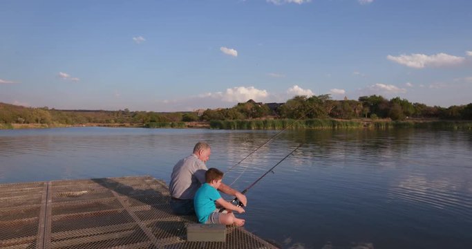 Grandfather and grandson fishing at a small lake