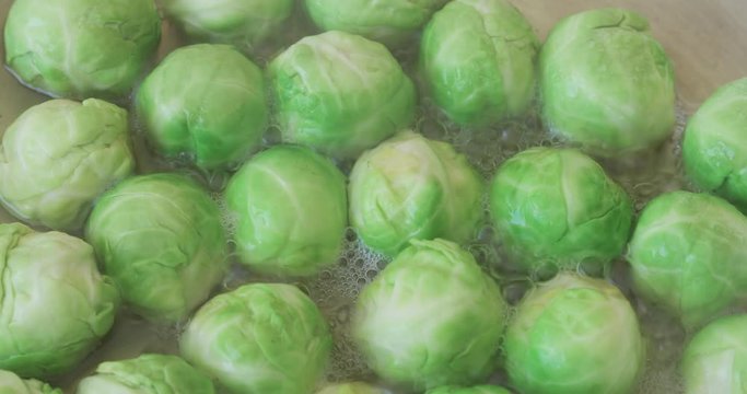 Close-up static shot of bright green brussel sprouts cooking in a pan