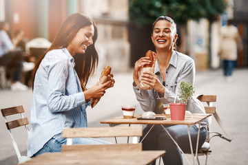 Two Female Friends Having Good Time Outdoors Eating Sandwiches
