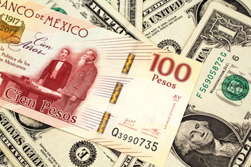 A close up image of a one hundred Mexican peso bank note with American one dollar bills in macro