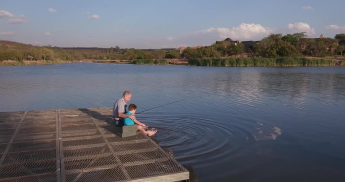 Grandfather and grandson fishing at a small lake
