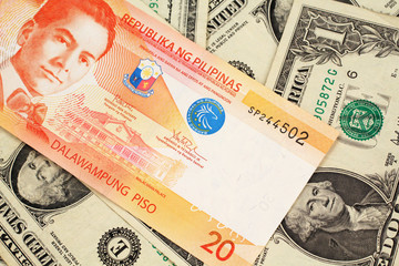 An orange twenty piso bank note from the Philippines with American one dollar bills close up in macro