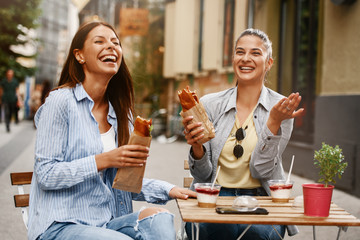Two Female Friends Having Good Time Outdoors Eating Sandwiches