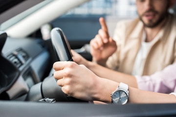 cropped view of woman driving car near man pointing with finger
