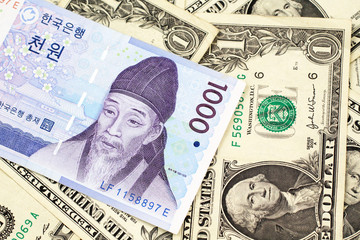 Obraz na płótnie Canvas A blue South Korean one thousand won bank note close up in macro on a background of American one dollar bills