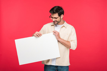 smiling handsome man holding empty board Isolated On pink