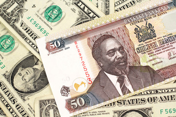 A close up image of a fifty Kenyan shilling bank note in macro with American one dollar bills